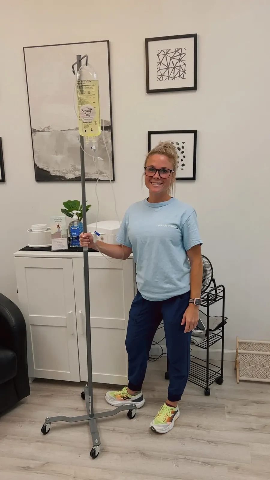 Tiffany, RN, standing beside an IV pole